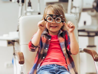 Little boy looking at camera and smiling while sitting on chair at the ophthalmologist